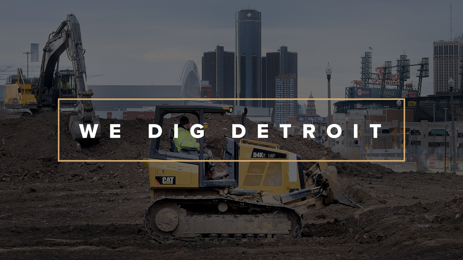 An excavator moving dirt in front of the Detroit skyline