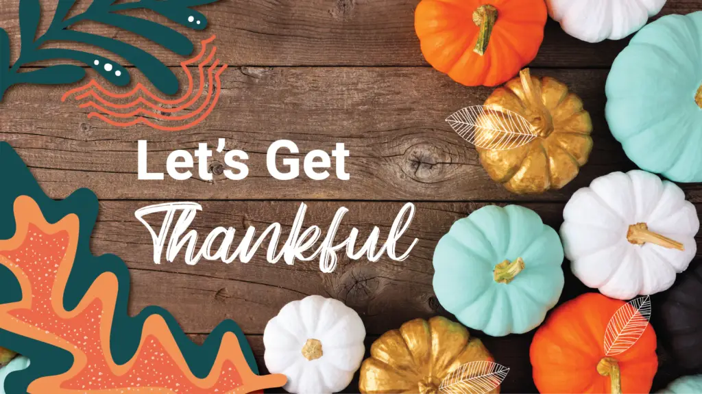 An array of different colored pumpkins sit on top of a wooden table "Let's Get Thankful"