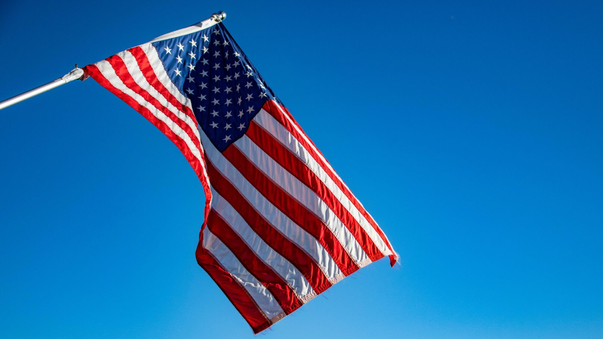 An american flag flying in front of a blue sky