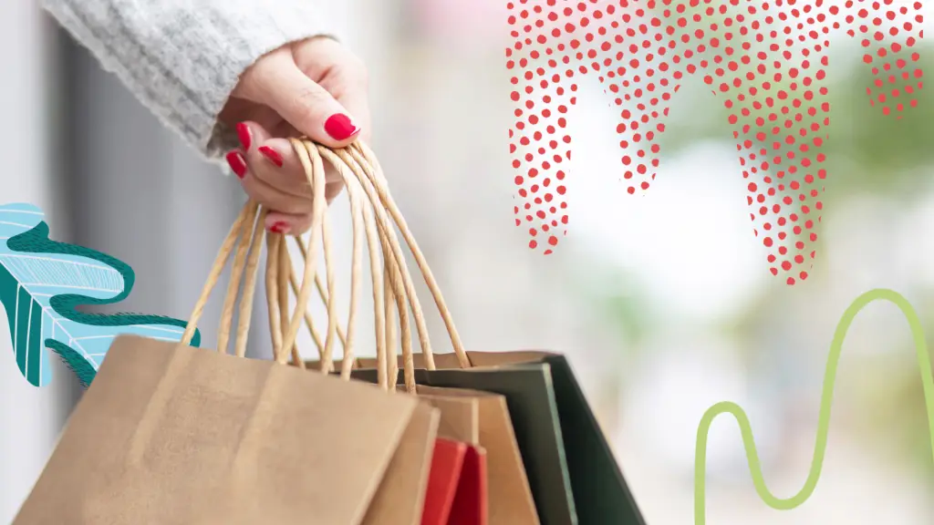 A woman holds shopping bags in her hand.