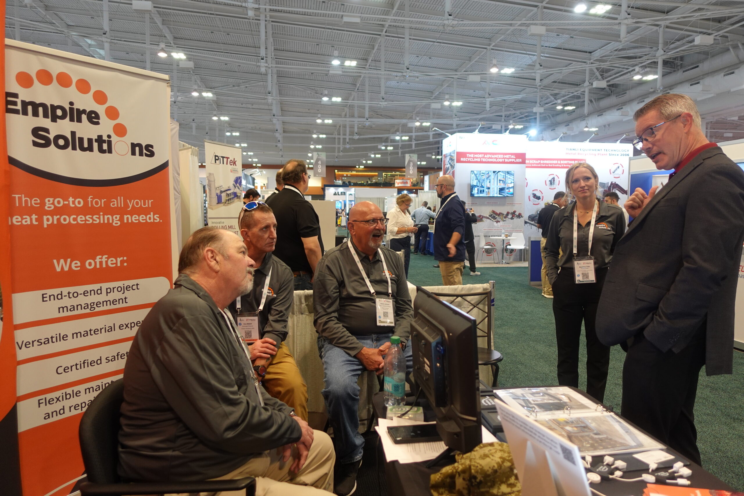 Three members of the Empire Solutions team sit together at a conference while speaking to a customer