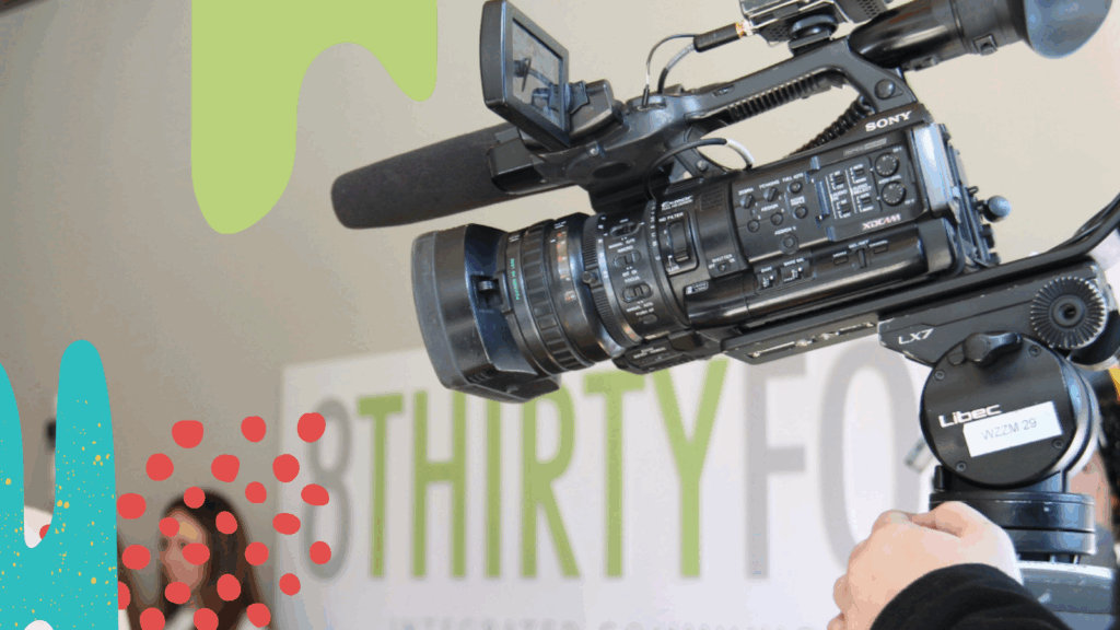 A local news camera films in front of the 8THIRTYFOUR sign.