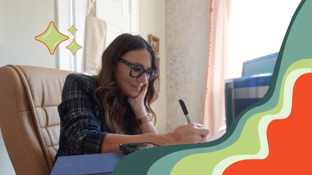 Kim in her office writing in her notebook while talking on the phone with a reporter