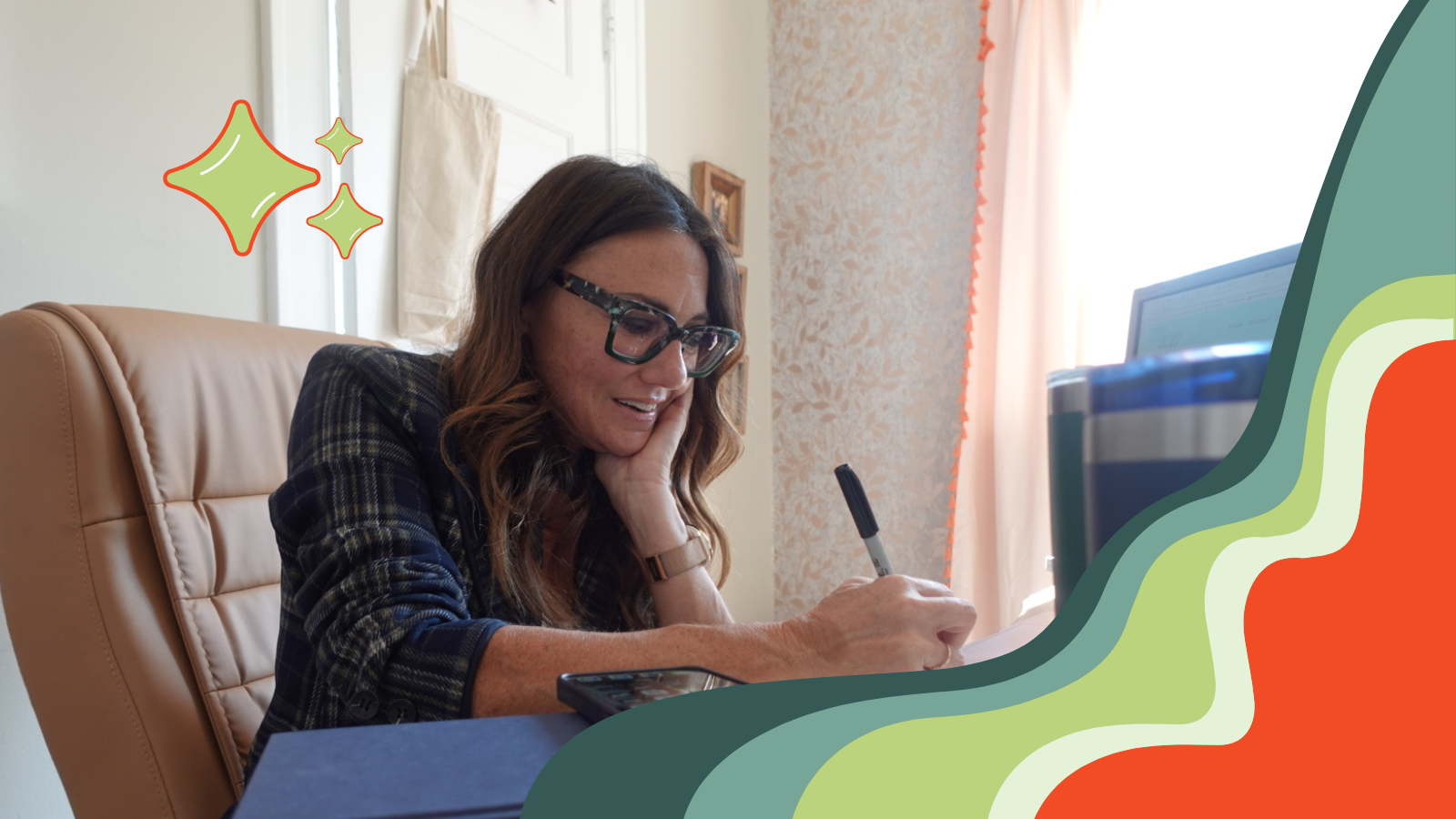 Kim in her office writing in her notebook while talking on the phone with a reporter