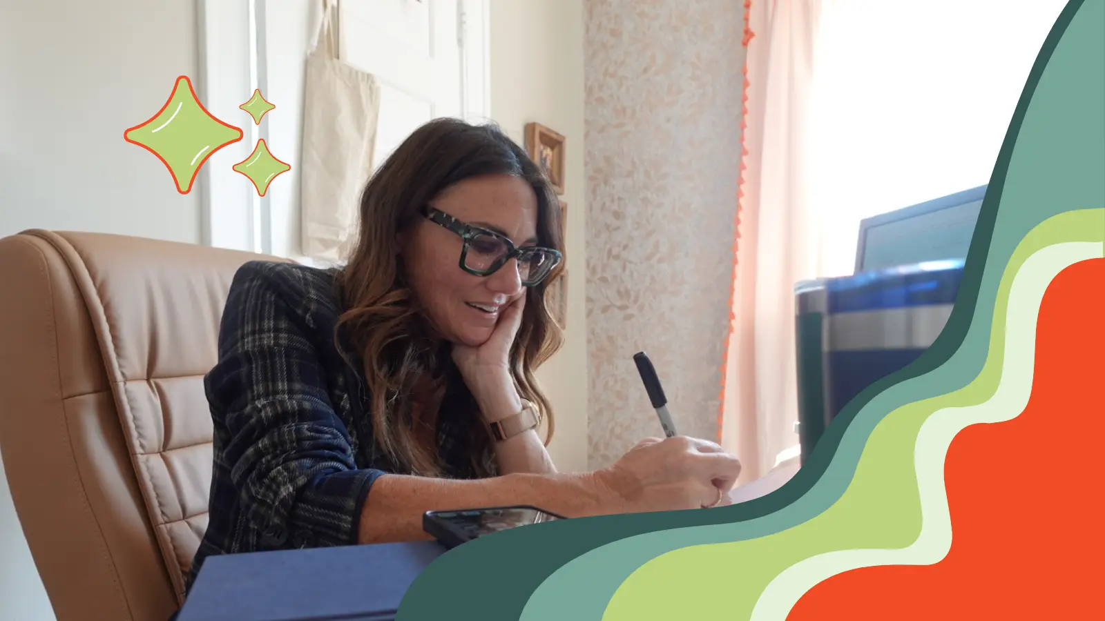 Kim in her office writing in her notebook while talking on the phone with a reporter