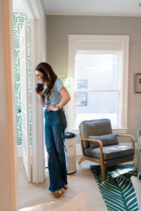 A woman leans against a doorway in an office staring pensively into it. 