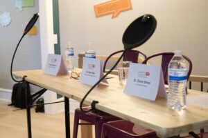 Panel table set up with microphones, water bottles and name cards for a perimenopause discussion featuring three guest panelists.